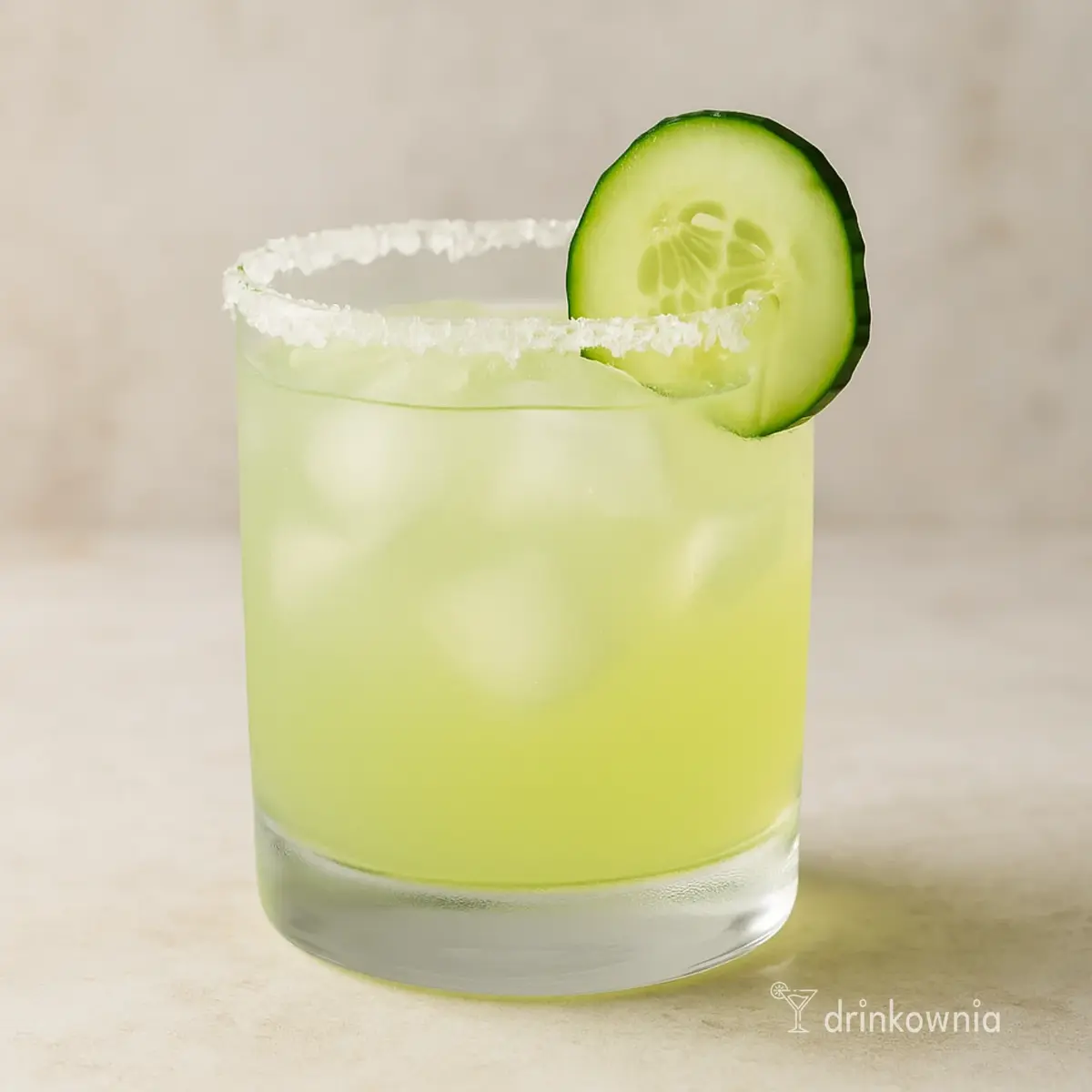 Ogórkowa Margarita w szklance old fashioned z kostkami lodu, soloną obręczą i plasterkiem ogórka – świeży drink na lato.
